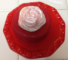 a red plate with a white frosted rose on it