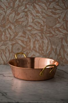 a large copper pan sitting on top of a marble counter