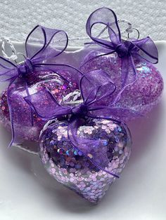 two purple heart shaped ornaments in a white bowl