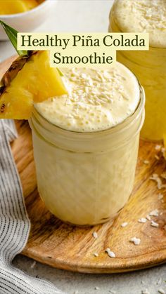 pineapple and coconut smoothie in mason jars on a wooden plate with fresh pineapple slices