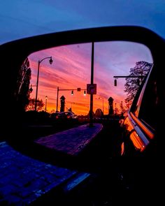 the sun is setting behind a car's rear view mirror