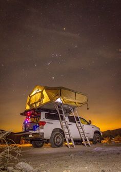 a white truck with a yellow tent on the roof and ladders up to it