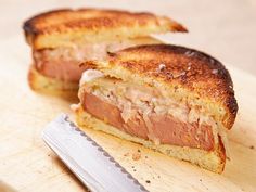 a sandwich cut in half sitting on top of a cutting board next to a knife