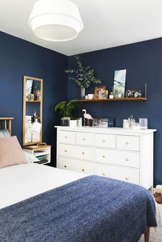 a bedroom with blue walls and white furniture