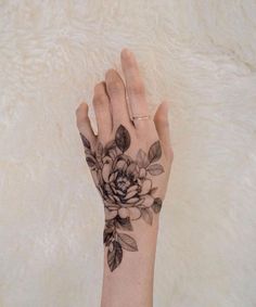 a woman's hand with a flower tattoo on it