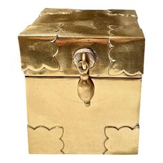 a gold colored metal box sitting on top of a white surface with scalloped edges