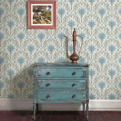 an old dresser with a painting on the wall next to it and a blue chest of drawers