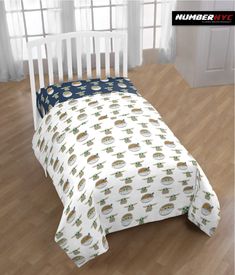 a white crib bed with blue and green bedspread on top of it