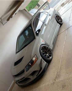 a silver sports car parked in a garage next to a white wall and window sill