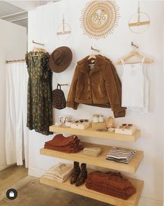 a clothing store display with clothes and hats on shelves in front of a wall mounted sunburst