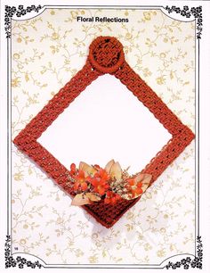 a crocheted square with flowers in the center on a floral wall hanging frame