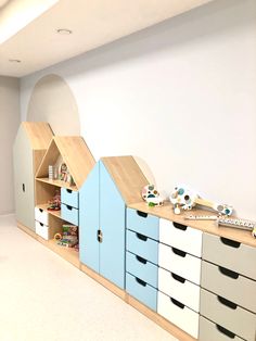 an empty room with several toy houses on top of it's shelves and drawers