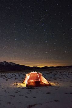 a tent pitched up in the desert under a night sky filled with stars and lightening