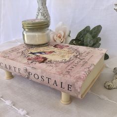 a candle sits on top of a book with a jar sitting on it's cover