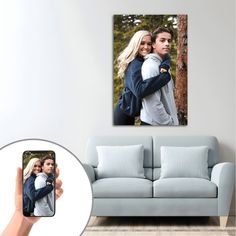 a person holding a cell phone in front of a wall with a photo on it