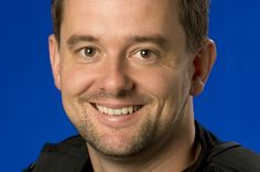 a man smiling for the camera in front of a blue background