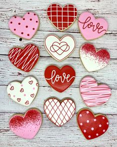 valentine's day decorated cookies arranged in the shape of hearts on a wooden table