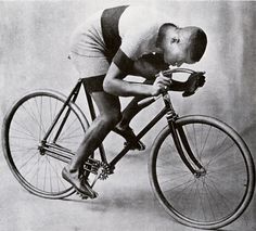 an old black and white photo of a man on a bicycle with his head in the air