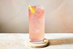 a tall glass filled with pink lemonade sitting on top of a white marble table