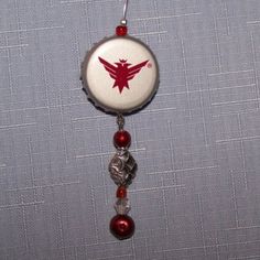 a red and white badge hanging from a hook on a gray fabric background with beads