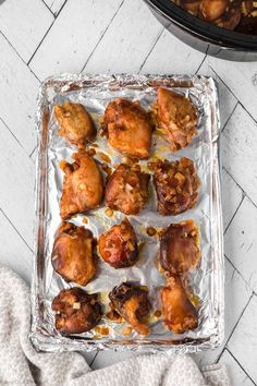 baked chicken wings on tin foil in an oven next to a casserole dish