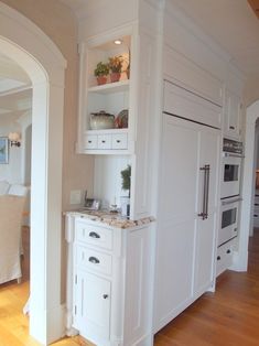 a kitchen with white cabinets and an island in the middle of the room that is built into the wall