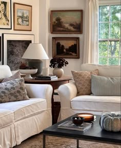 a living room filled with white furniture and pictures on the wall above it's windows