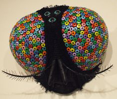 a black mannequin's head with multicolored circles on the top