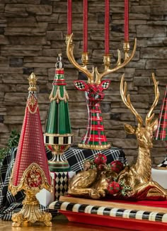 an assortment of christmas decorations on display in front of a stone wall with candlesticks