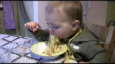 a young child eating spaghetti from a bowl