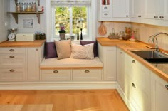 a kitchen filled with lots of white cabinets and counter top space next to a window