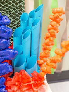 some orange and blue candy sticks are on the table next to other colorful items in front of a window