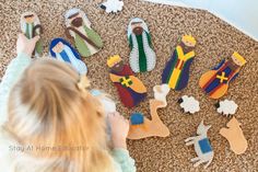 a child playing with felt nativity toys on the floor