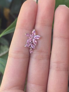 a woman's hand holding a pink ring with leaves on the top and bottom