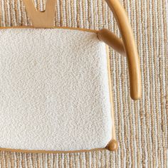 a wooden chair with a white cushion on top of it and a brown handle next to it