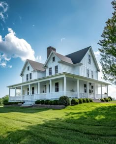 a large white house sitting in the middle of a lush green field on a sunny day