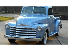 an old blue truck is parked in a driveway