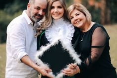 two women and a man are posing for a photo while holding a feathered object