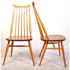 two wooden chairs sitting next to each other on a white floor with no one in them