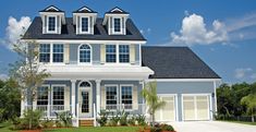 a white house with three dormers and two garages on the front lawn area