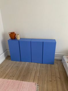 a blue cabinet sitting on top of a hard wood floor next to a bed and rug