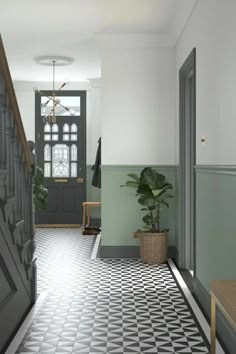 an entryway with black and white tile flooring, potted plant on the far side