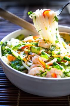 a bowl filled with shrimp and vegetables being held by a fork