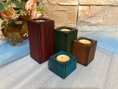 three candles sitting on top of a table next to flowers