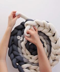 a woman is holding a large rope with buttons on it and making something out of it