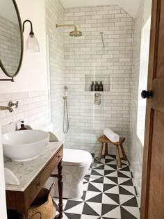 a white toilet sitting next to a sink in a bathroom under a mirror and a wooden door