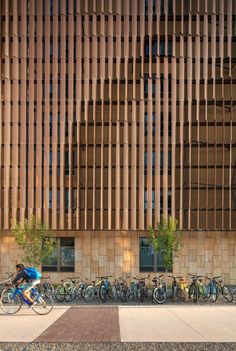 several bicycles parked in front of a building with wooden slats on the facade and side