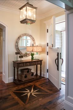 a foyer with a mirror, table and lamp