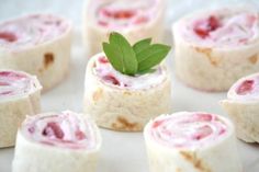 there are several rolls on the plate with strawberries in the background and one is cut into small pieces