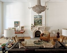 a living room filled with furniture and a chandelier hanging from the ceiling over a fire place